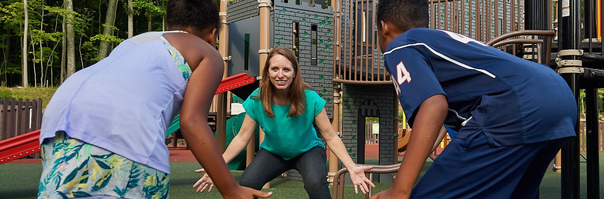 Lindsay Distefano, associate professor of kinesiology,shows children how to exercise on a playground at the Mansfield Community Center